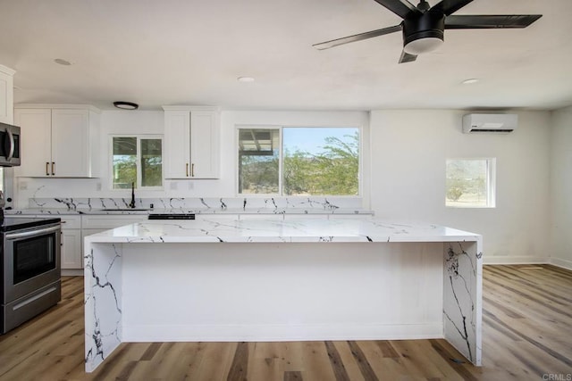 5655 Last Mile Rd, Johnson Valley, CA 92285 - kitchen with appliances with stainless steel finishes, a wall unit AC, light wood-type flooring, light stone counters, and recessed lighting