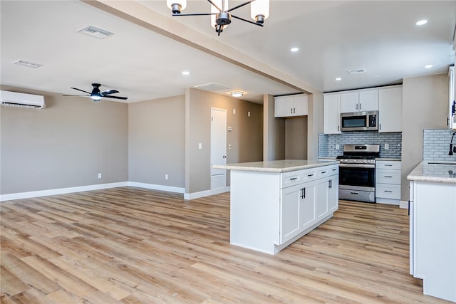 73570 Cedar Dr Unit 29, Palms, CA 92277 - kitchen with appliances with stainless steel finishes, a wall unit AC, decorative backsplash, light wood finished floors, and white cabinets