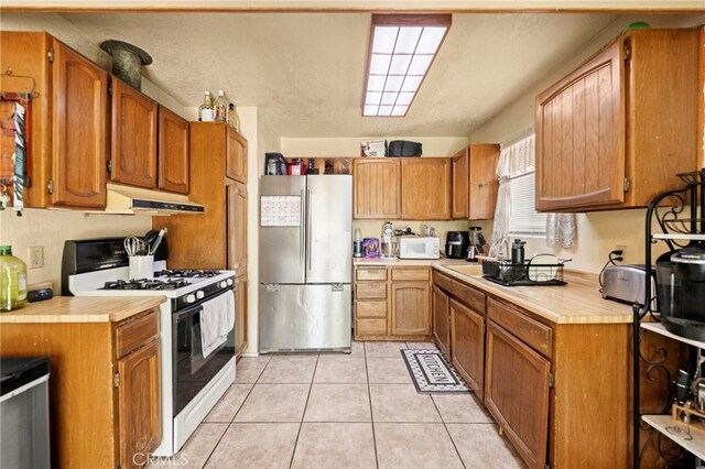 27636 Ethanac Rd, Menifee, CA 92585 - kitchen featuring white appliances, under cabinet range hood, light countertops, light tile patterned flooring, and brown cabinets