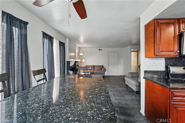 13905 Caspian Way, Moreno Valley, CA 92553 - kitchen featuring open floor plan, a fireplace, dark stone counters, and ceiling fan