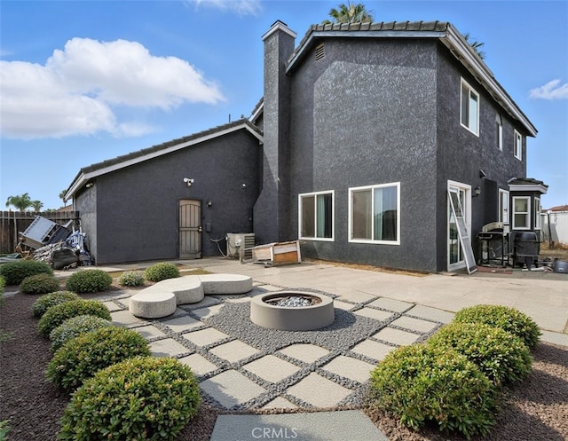 13905 Caspian Way, Moreno Valley, CA 92553 - back of house featuring a patio area, an outdoor fire pit, stucco siding, and a chimney