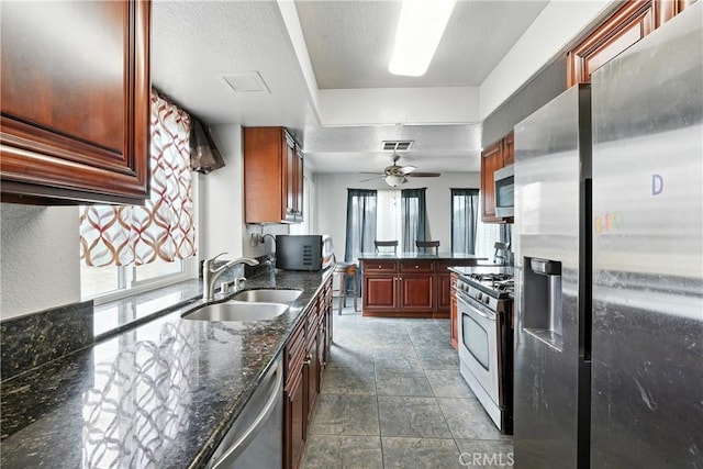 13905 Caspian Way, Moreno Valley, CA 92553 - kitchen featuring stainless steel appliances, dark stone counters, ceiling fan, and dark stone finish flooring
