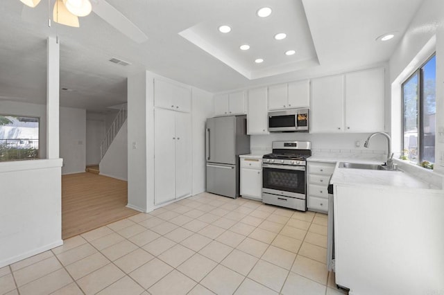 3418 Seabreeze Walk, Oceanside, CA 92056 - kitchen with appliances with stainless steel finishes, recessed lighting, white cabinets, a tray ceiling, and ceiling fan