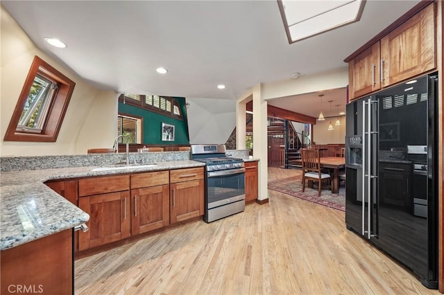 8201 W W Side Potter Valley Rd, Potter Valley, CA 95469 - kitchen with stainless steel gas range oven, light wood-style flooring, brown cabinets, light stone counters, and black refrigerator with ice dispenser