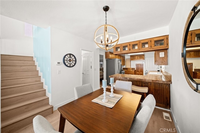 1924 W Oceanfront, Newport Beach, CA 92663 - dining space with a chandelier, stairs, and light wood-type flooring