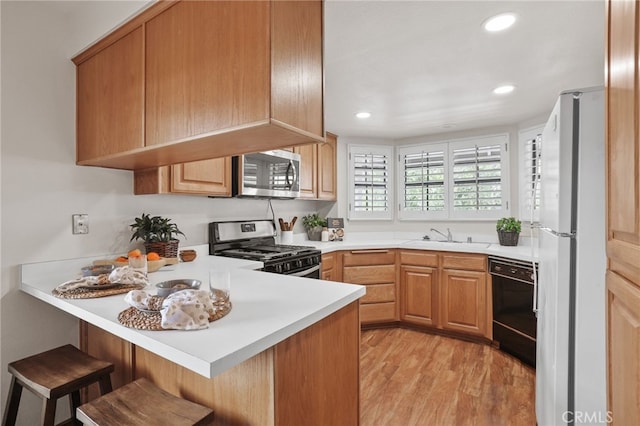 4809 Fieldbrook Ln, Cypress, CA 90630 - kitchen featuring stainless steel appliances, a peninsula, a kitchen bar, light wood finished floors, and light countertops