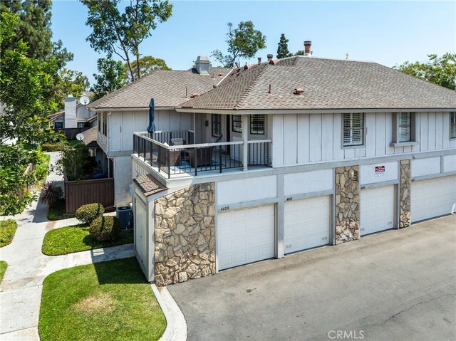 4809 Fieldbrook Ln, Cypress, CA 90630 - back of property with roof with shingles, board and batten siding, a garage, stone siding, and driveway