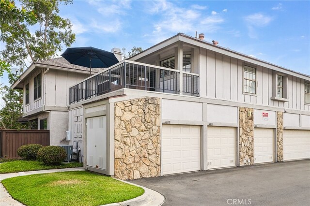 4809 Fieldbrook Ln, Cypress, CA 90630 - rear view of property with stone siding, asphalt driveway, a balcony, a garage, and board and batten siding