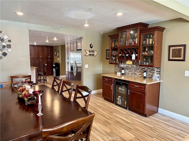 9150 Boxwood Ave, Fontana, CA 92335 - indoor dry bar with beverage cooler, stainless steel refrigerator with ice dispenser, decorative backsplash, a textured ceiling, and light wood-style flooring