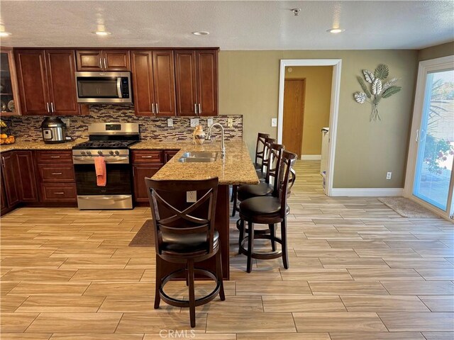 9150 Boxwood Ave, Fontana, CA 92335 - kitchen with appliances with stainless steel finishes, a breakfast bar, a peninsula, light wood finished floors, and backsplash