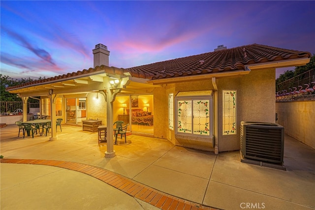 19809 Winged Foot Way, Porter Ranch, CA 91326 - back of house at dusk with a chimney, a patio, a tiled roof, stucco siding, and outdoor dining area