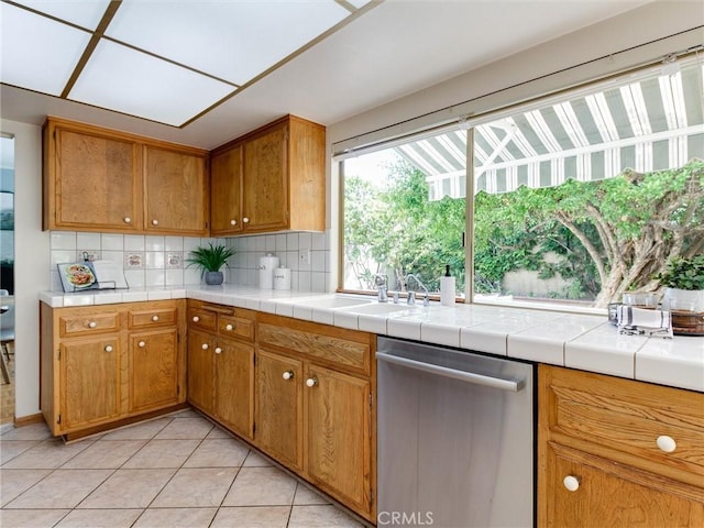 9386 Cambridge St, Cypress, CA 90630 - kitchen featuring stainless steel dishwasher, tasteful backsplash, light tile patterned floors, and brown cabinets