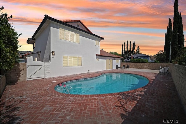 19040 Celtic St, Porter Ranch, CA 91326 - pool at dusk featuring a fenced backyard, a patio, and a gate