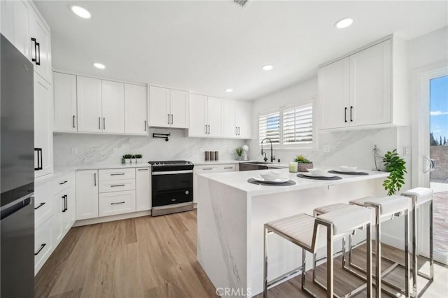 19040 Celtic St, Porter Ranch, CA 91326 - kitchen with stainless steel appliances, light countertops, a kitchen bar, light wood-style flooring, and recessed lighting