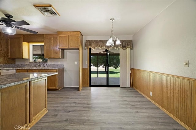 8140 Sherwood Blvd, Los Molinos, CA 96055 - kitchen featuring a chandelier, wainscoting, light wood-type flooring, a ceiling fan, and brown cabinets
