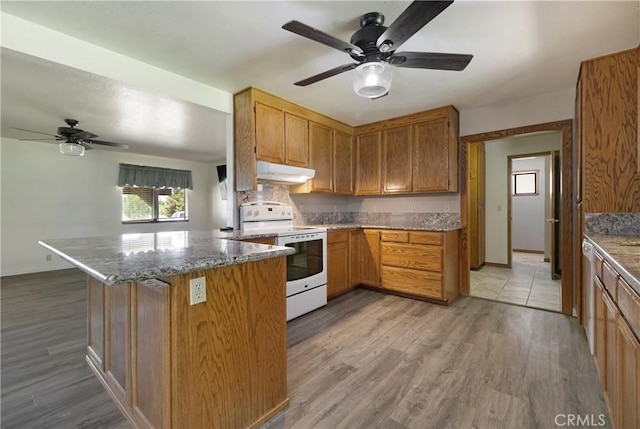 8140 Sherwood Blvd, Los Molinos, CA 96055 - kitchen with white electric stove, ceiling fan, under cabinet range hood, stone counters, and light wood-type flooring