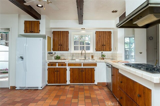 611 E Mountain St, Glendale, CA 91207 - kitchen with appliances with stainless steel finishes, beamed ceiling, tile counters, brown cabinets, and wall chimney exhaust hood
