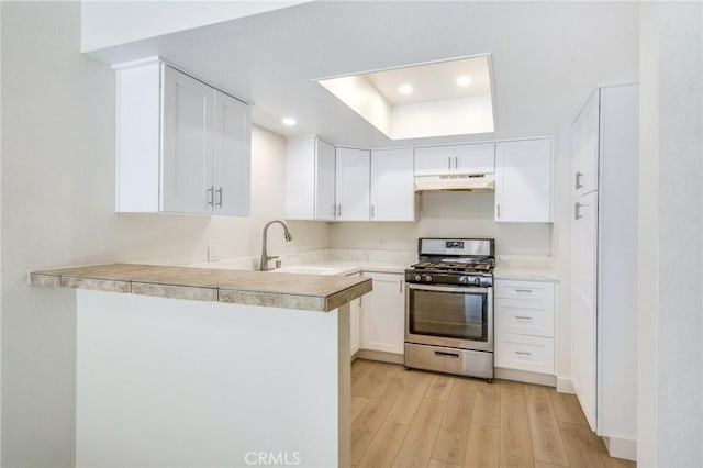 1413 Vista Grande Unit 122, Fullerton, CA 92835 - kitchen with stainless steel range with gas stovetop, under cabinet range hood, a peninsula, white cabinetry, and recessed lighting