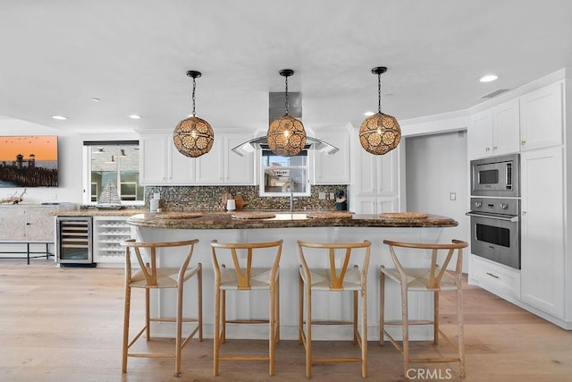 516 S The Strand # A, Oceanside, CA 92054 - kitchen with appliances with stainless steel finishes, beverage cooler, white cabinetry, tasteful backsplash, and recessed lighting