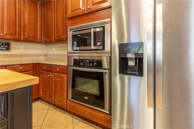 2168 Stonewood St, Mentone, CA 92359 - kitchen featuring stainless steel appliances, light tile patterned floors, light stone countertops, and brown cabinetry