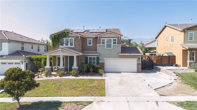 2168 Stonewood St, Mentone, CA 92359 - craftsman-style house with concrete driveway, roof mounted solar panels, stone siding, a porch, and a gate