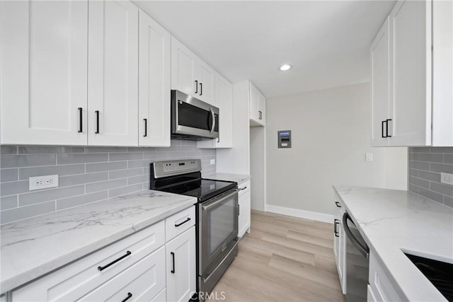 503 Saint Andrews Rd Unit E, Newport Beach, CA 92663 - kitchen featuring stainless steel appliances, light wood finished floors, light stone countertops, white cabinetry, and backsplash