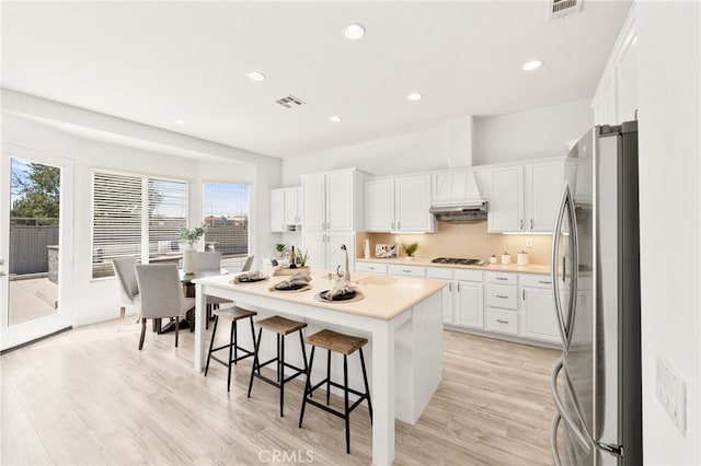 40065 Temple Ct, Murrieta, CA 92563 - kitchen featuring freestanding refrigerator, white cabinetry, a kitchen bar, light countertops, and a center island with sink