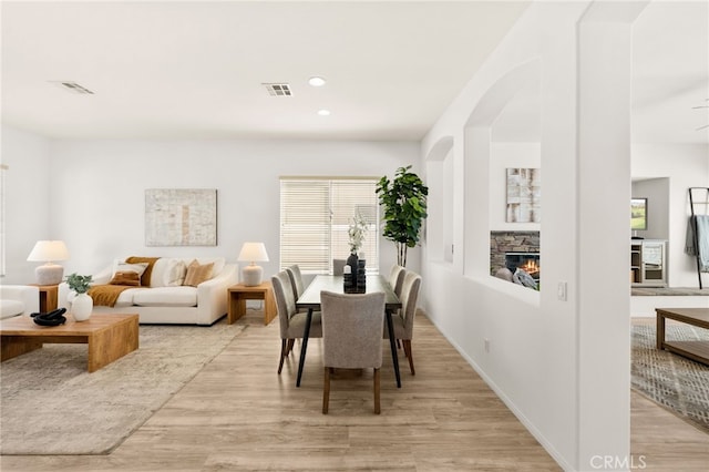 40065 Temple Ct, Murrieta, CA 92563 - dining space with light wood finished floors, a fireplace, arched walkways, and recessed lighting