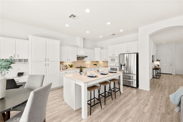 40065 Temple Ct, Murrieta, CA 92563 - kitchen with white appliances, arched walkways, white cabinets, a breakfast bar, and recessed lighting