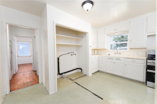 7086 Fairfax Dr, San Bernardino, CA 92404 - kitchen featuring gas range, white cabinetry, decorative backsplash, and healthy amount of natural light