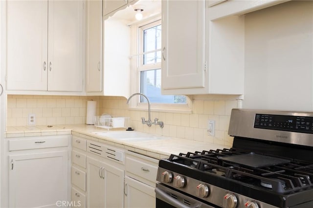 7086 Fairfax Dr, San Bernardino, CA 92404 - kitchen featuring stainless steel range with gas stovetop, white cabinets, tile counters, and tasteful backsplash