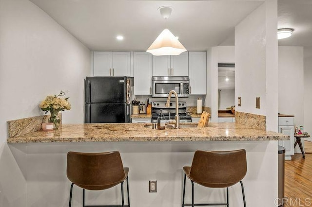 6009 Rancho Mission Rd Unit 102, San Diego, CA 92108 - kitchen with stainless steel microwave, freestanding refrigerator, a peninsula, light stone countertops, and stove