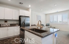 16540 Wyndham Ln Unit 10, Fontana, CA 92336 - kitchen with stainless steel appliances, dark stone counters, white cabinetry, recessed lighting, and an island with sink