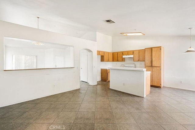 16205 Seville Ave, Fontana, CA 92335 - kitchen with light countertops, brown cabinetry, under cabinet range hood, tile patterned flooring, and an island with sink