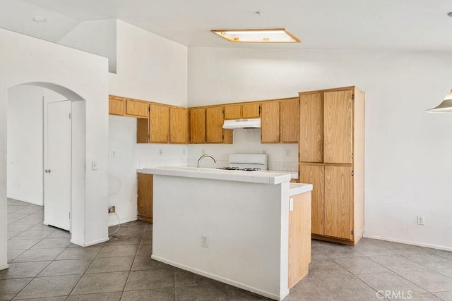 16205 Seville Ave, Fontana, CA 92335 - kitchen featuring under cabinet range hood, range, high vaulted ceiling, light tile patterned floors, and arched walkways