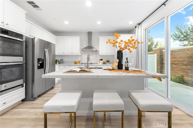 16471 Globetrotter St, Chino, CA 91708 - kitchen with appliances with stainless steel finishes, wall chimney exhaust hood, light countertops, white cabinets, and light wood finished floors