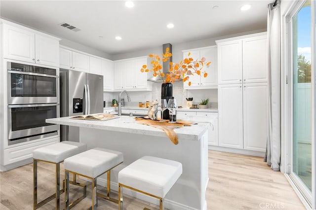 16471 Globetrotter St, Chino, CA 91708 - kitchen featuring stainless steel appliances, white cabinetry, a breakfast bar area, light wood-type flooring, and recessed lighting