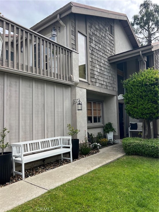 27076 Mill Pond Rd W Unit 9, Dana Point, CA 92624 - view of property exterior with a balcony, stucco siding, and a yard