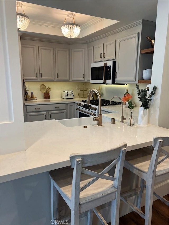 27076 Mill Pond Rd W Unit 9, Dana Point, CA 92624 - kitchen featuring ornamental molding, a breakfast bar, gray cabinets, a peninsula, and light countertops
