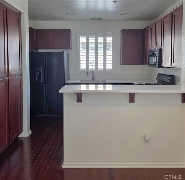 1652 Hickory Nut Pl, Chula Vista, CA 91915 - kitchen featuring black appliances, a peninsula, light countertops, dark wood-style floors, and a breakfast bar area