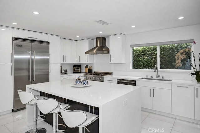 24523 Via Esquina, Calabasas, CA 91302 - kitchen featuring wall chimney exhaust hood, stainless steel appliances, a center island, a breakfast bar, and white cabinets