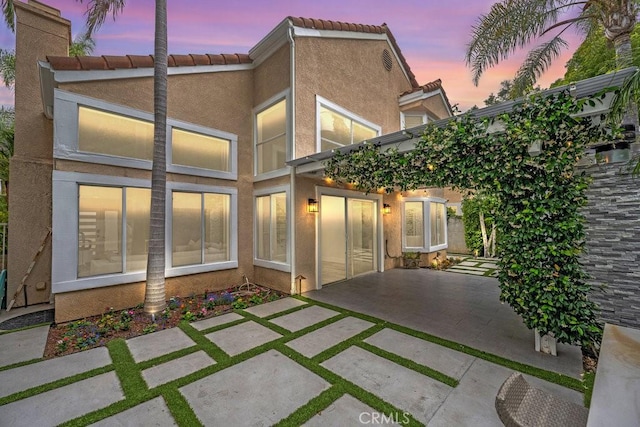 24523 Via Esquina, Calabasas, CA 91302 - back of property at dusk with a patio, a tiled roof, and stucco siding