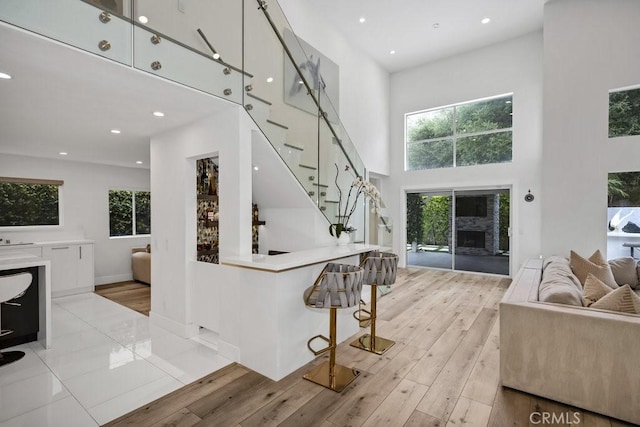 24523 Via Esquina, Calabasas, CA 91302 - living room featuring a fireplace, a towering ceiling, light wood-style flooring, healthy amount of natural light, and stairs