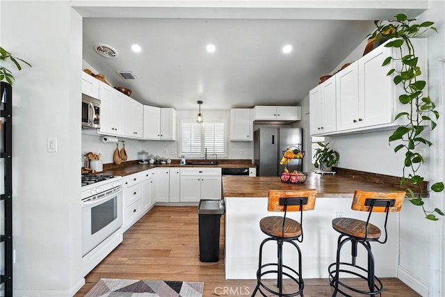 951 W Olive St, Corona, CA 92882 - kitchen with stainless steel appliances, a peninsula, a kitchen breakfast bar, wooden counters, and white cabinets
