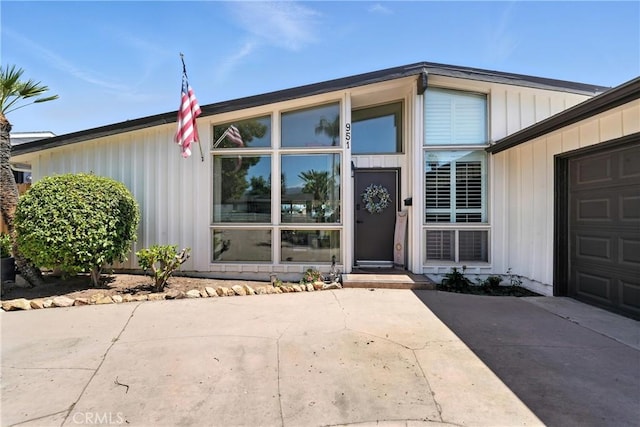 951 W Olive St, Corona, CA 92882 - view of exterior entry with a garage, driveway, and board and batten siding