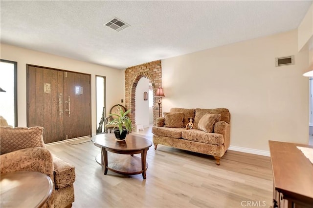 1582 Hardt St, San Bernardino, CA 92408 - living area with arched walkways, light wood-style flooring, and a textured ceiling