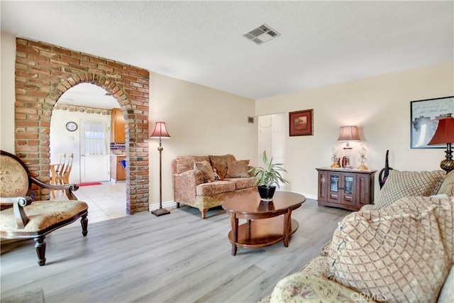 1582 Hardt St, San Bernardino, CA 92408 - living area with light wood-style floors, arched walkways, and a textured ceiling
