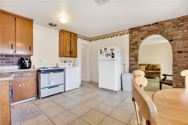 1582 Hardt St, San Bernardino, CA 92408 - kitchen with white appliances, washer / dryer, light tile patterned flooring, light countertops, and arched walkways