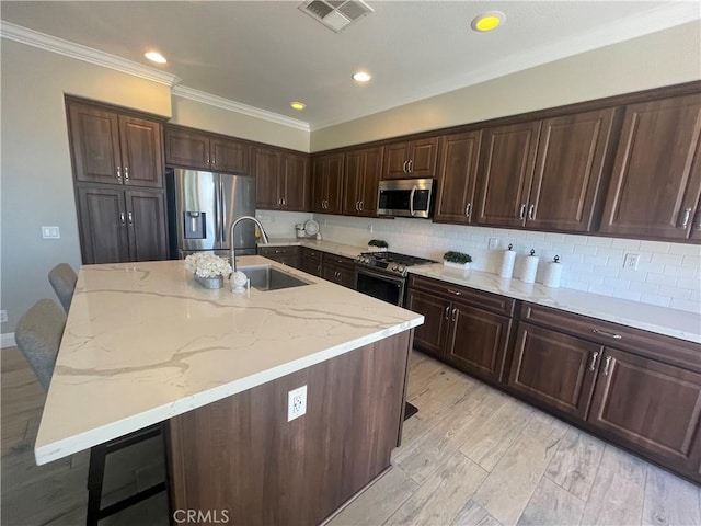 29 Spring View Way, Rancho Santa Margarita, CA 92688 - kitchen with stainless steel appliances, crown molding, light stone countertops, a breakfast bar area, and a center island with sink
