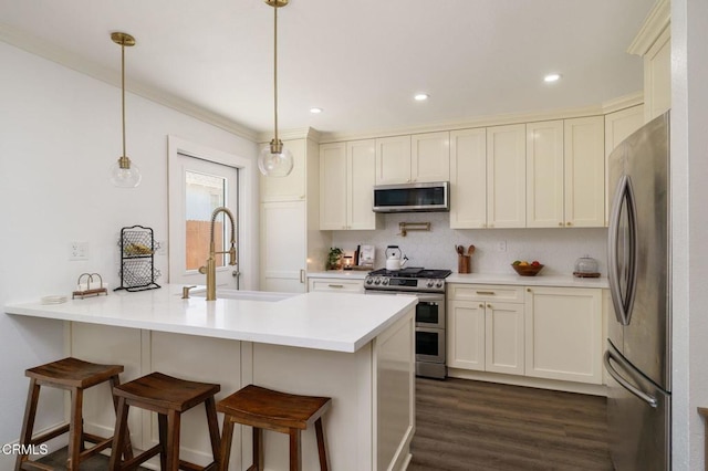 208 S 4th St, Santa Paula, CA 93060 - kitchen with appliances with stainless steel finishes, a peninsula, a breakfast bar area, dark wood-style floors, and pendant lighting